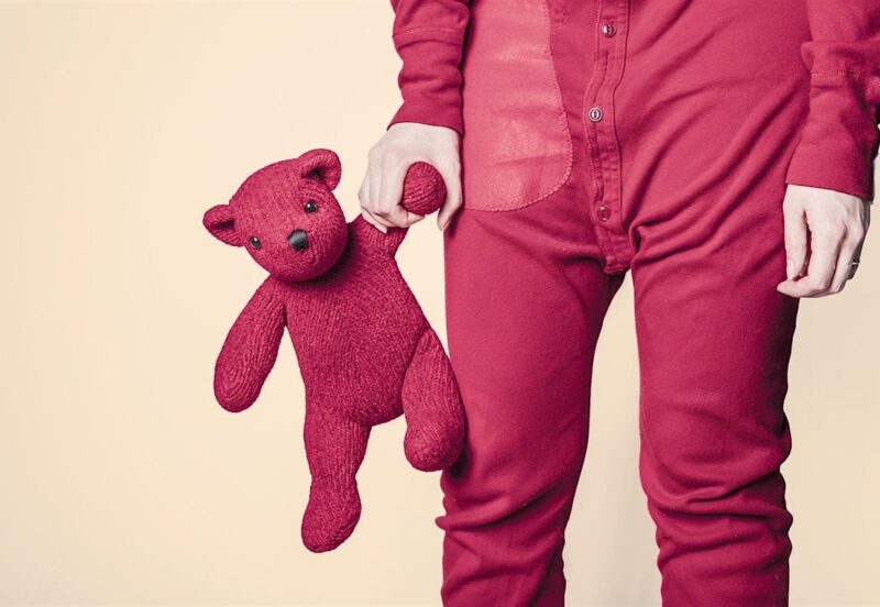 Child in red pyjamas holding a teddy bear